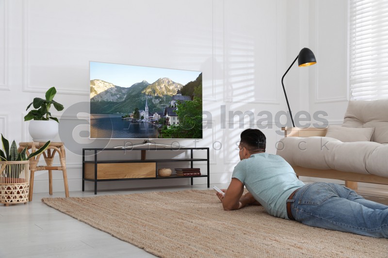 Photo of Man watching television at home. Living room interior with TV on stand