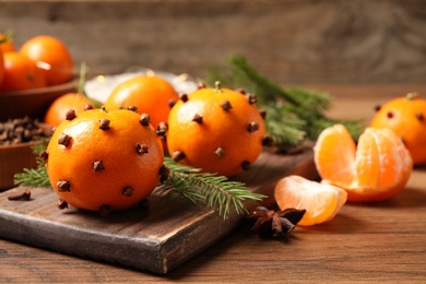 Delicious fresh tangerines with cloves on wooden table. Christmas celebration
