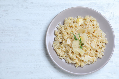 Photo of Delicious risotto with cheese on white wooden table, top view