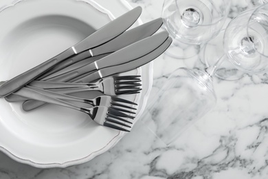Photo of Plates with cutlery and glasses on white marble table, top view