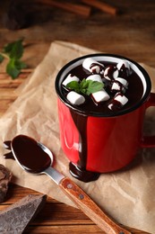 Mug of delicious hot chocolate with marshmallows and fresh mint served on wooden table
