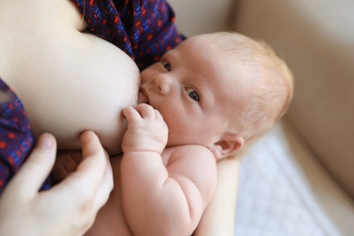 Woman breast feeding her little baby at home, closeup