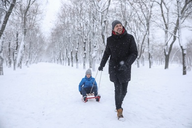 Photo of Father sledding his child outside on winter day. Christmas vacation