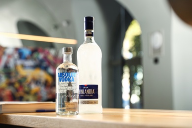 Photo of MYKOLAIV, UKRAINE - SEPTEMBER 23, 2019: Bottles of Finlandia and Absolut vodka on wooden counter in bar