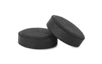 Activated charcoal pills on white background. Potent sorbent