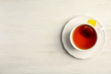 Cup of delicious tea with saucer on wooden background, top view