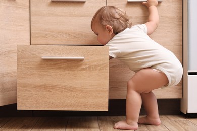 Little child exploring drawer indoors. Danger situation