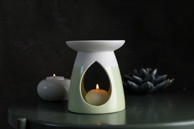 Aroma lamp with small candle on black table