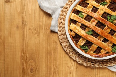 Photo of Freshly baked meat pie on wooden table, top view. Space for text