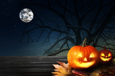 Image of Spooky Jack O Lantern pumpkins under full moon on Halloween. Space for text
