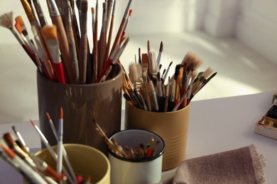 Different paintbrushes on white table indoors, closeup. Artist's workplace