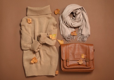 Flat lay composition with sweater and dry leaves on brown background. Autumn season