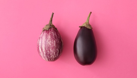 Raw ripe eggplants on pink background, flat lay