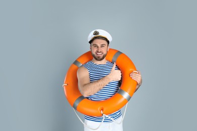Happy sailor with ring buoy on light grey background