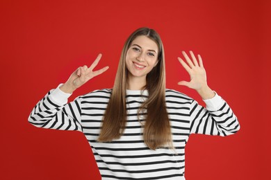Woman showing number seven with her hands on red background