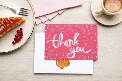 Photo of Card with phrase Thank You, cheesecake and coffee on light wooden table, flat lay