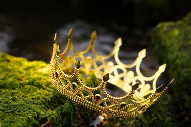 Photo of Beautiful golden crown on stones with green moss outdoors. Fantasy item