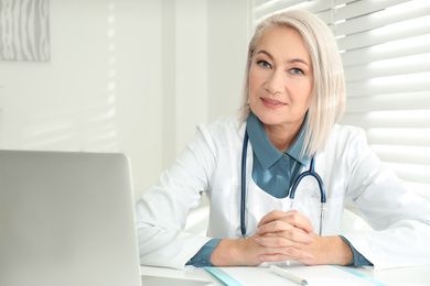 Portrait of mature female doctor in white coat at workplace