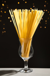 Uncooked spaghetti on grey table against blurred lights. Italian pasta