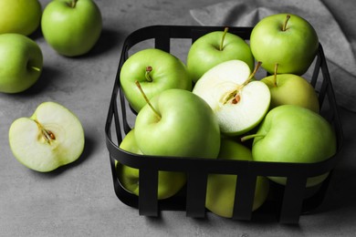 Black metal container full of apples on grey table, closeup