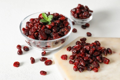 Tasty dried cranberries and leaves on white table