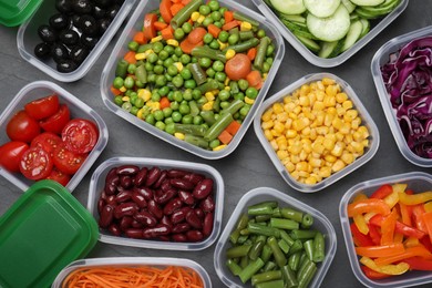 Set of plastic containers with fresh food on black table, flat lay