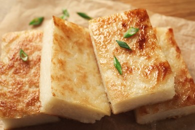 Delicious turnip cake with green onion on parchment paper, closeup