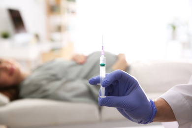 Doctor with syringe near pregnant woman in hospital, closeup. Vaccination concept