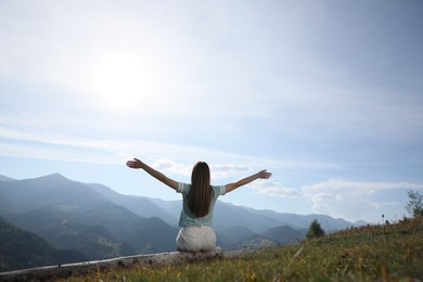 Photo of Young woman in peaceful mountains, back view. Feeling freedom