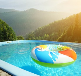 Colorful inflatable ring floating in outdoor swimming pool at luxury resort and beautiful view of mountains on sunny day