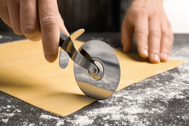 Woman making pasta at grey table, closeup