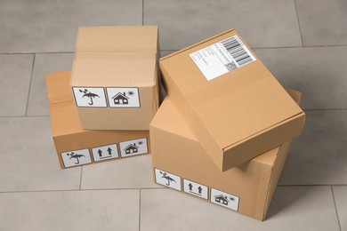 Many closed cardboard boxes with packaging symbols on floor. Delivery service