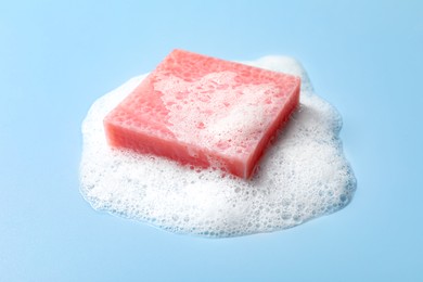 Soap and fluffy foam on light blue background