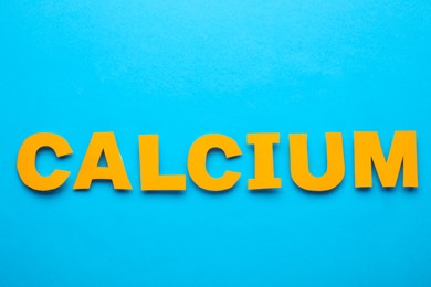 Word Calcium made of orange letters on light blue background, flat lay
