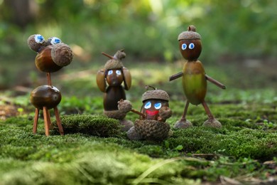 Photo of Cute figures made of acorns on green moss outdoors