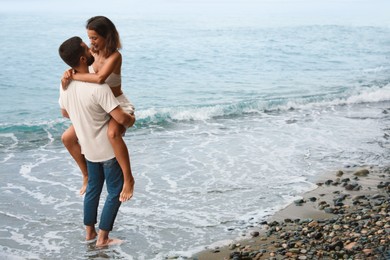 Happy young couple having fun on beach near sea. Space for text