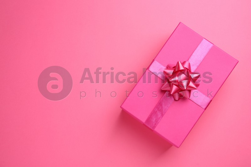 Beautiful gift box on pink background, top view. Space for text