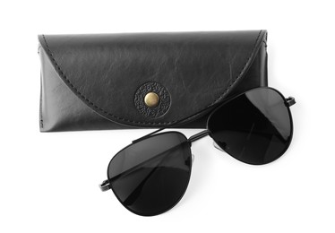 Stylish sunglasses and black leather case on white background, top view