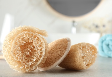 Photo of Natural loofah sponges on table in bathroom, closeup