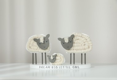 Photo of Cute decorative sheep and lamb figurine with phrase Dream Big Little One on white table against light background. Family Day