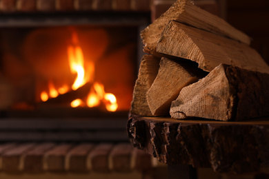 Photo of Pile of wood and blurred fireplace on background, space for text. Winter vacation