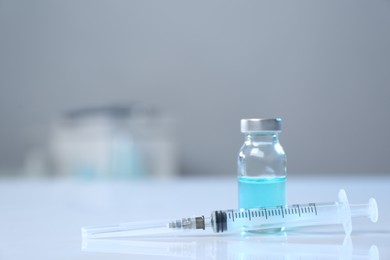 Syringe and vial on white table. Space for text