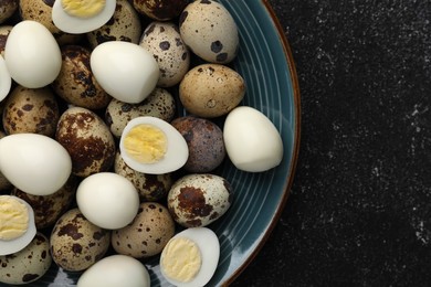 Photo of Peeled and unpeeled hard boiled quail eggs in plate on black table, top view