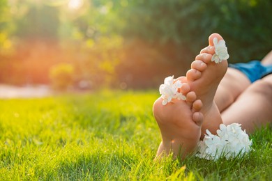 Photo of Teenage girl with beautiful hortensia flowers lying on green grass outdoors, closeup. Space for text