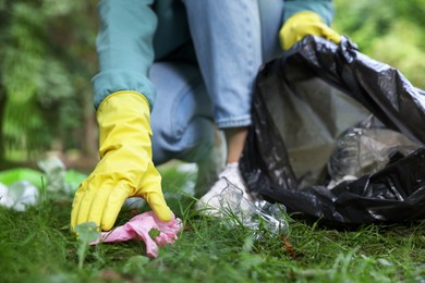 Photo of Woman with plastic bag collecting garbage in park, closeup