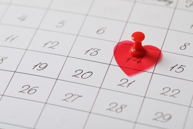 Calendar page with red pin and heart on Valentine's Day, closeup