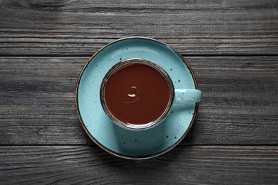Photo of Yummy hot chocolate in cup on black wooden table, top view