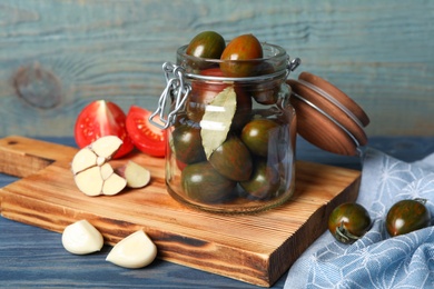 Pickling jar with fresh ripe tomatoes on blue wooden table