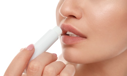 Young woman with cold sore applying lip balm against white background, closeup