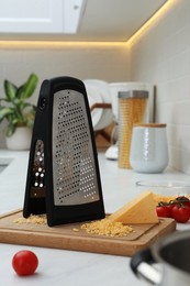 Grater, cheese and cherry tomatoes on kitchen counter